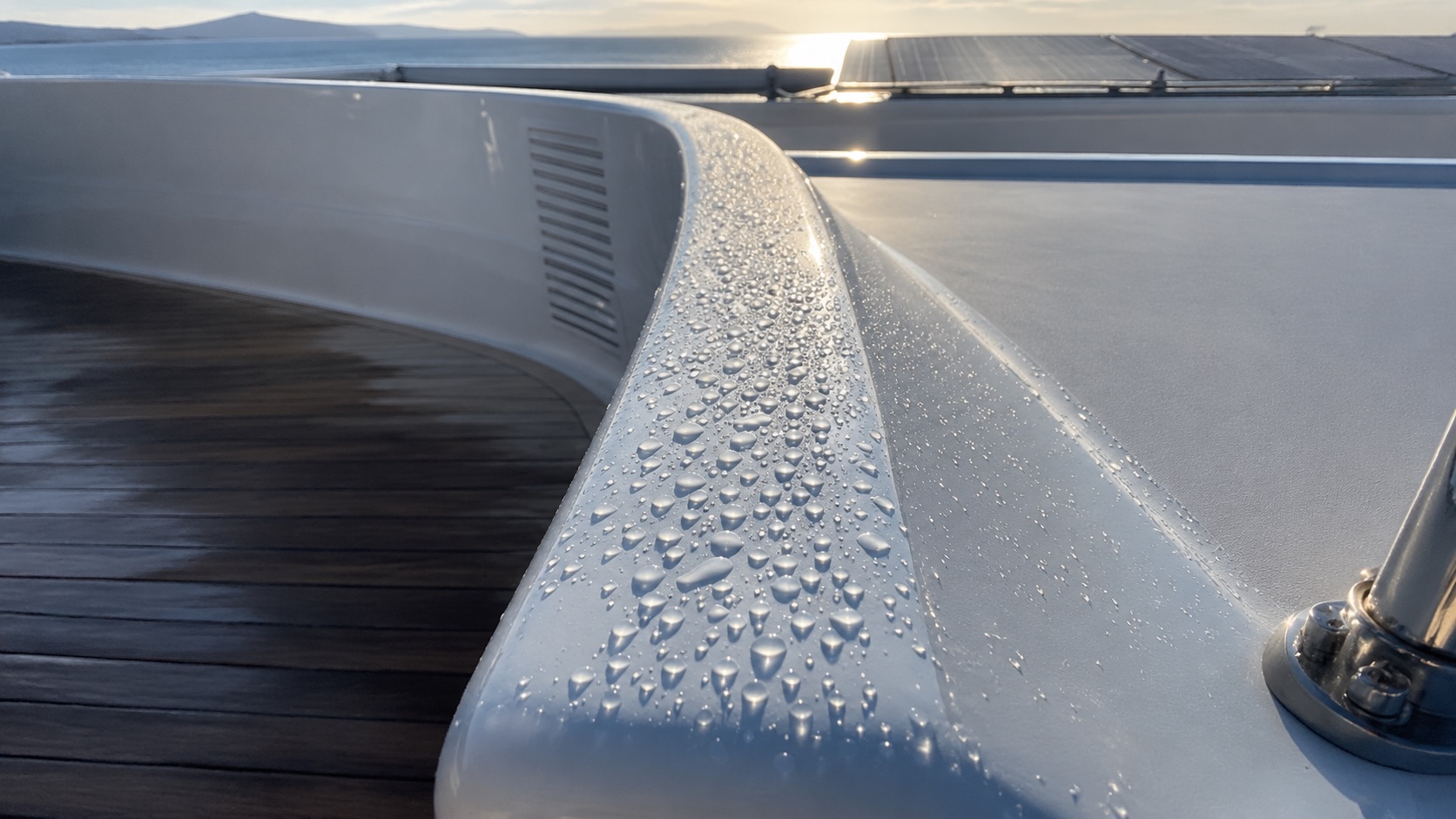 Water beading on the freshly protected paintwork of a superyacht bulwark.