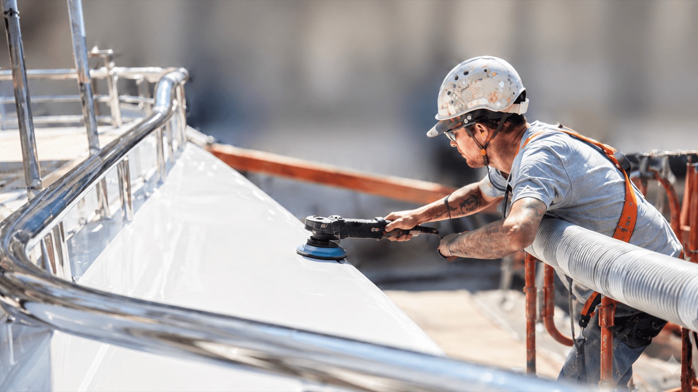 A technician machine-polishing the sheerline of the 74m Nobiskrug.